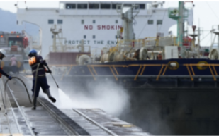 2 employés qui nettoient sur un port et un navire à quai